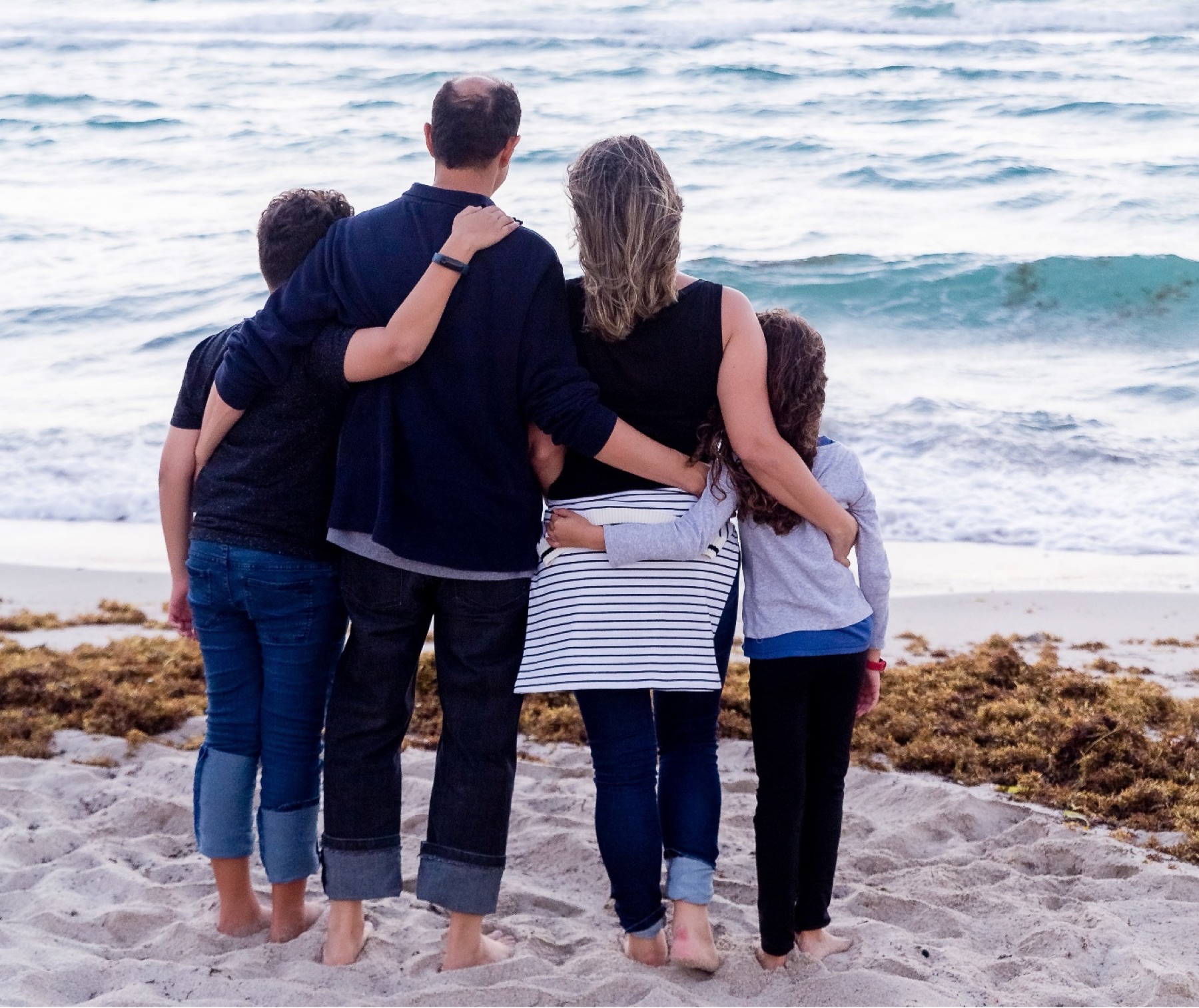 Family of four on the beach, looking out to sea