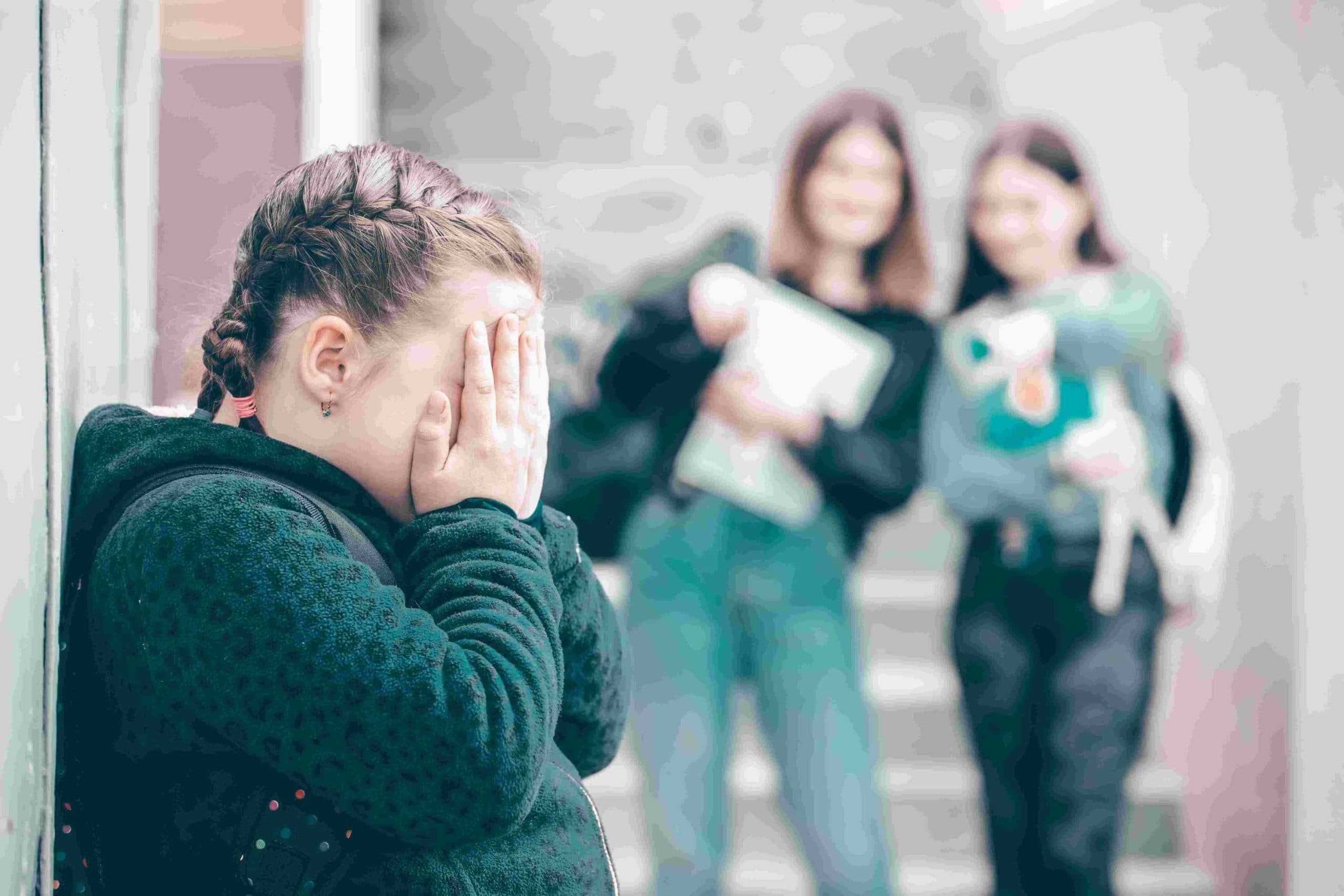 bullied child crying with other students in background